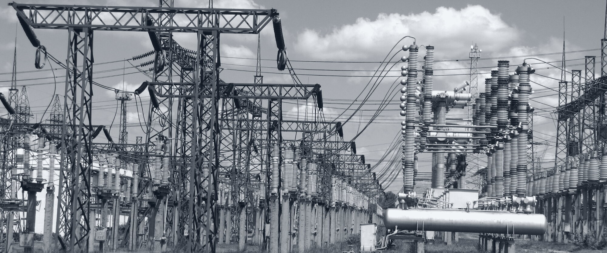 A high-voltage switchyard: lattice steel structures, insulator stacks, and overhead bus.